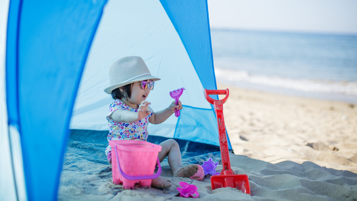 young child at the beach under a beach shelter
