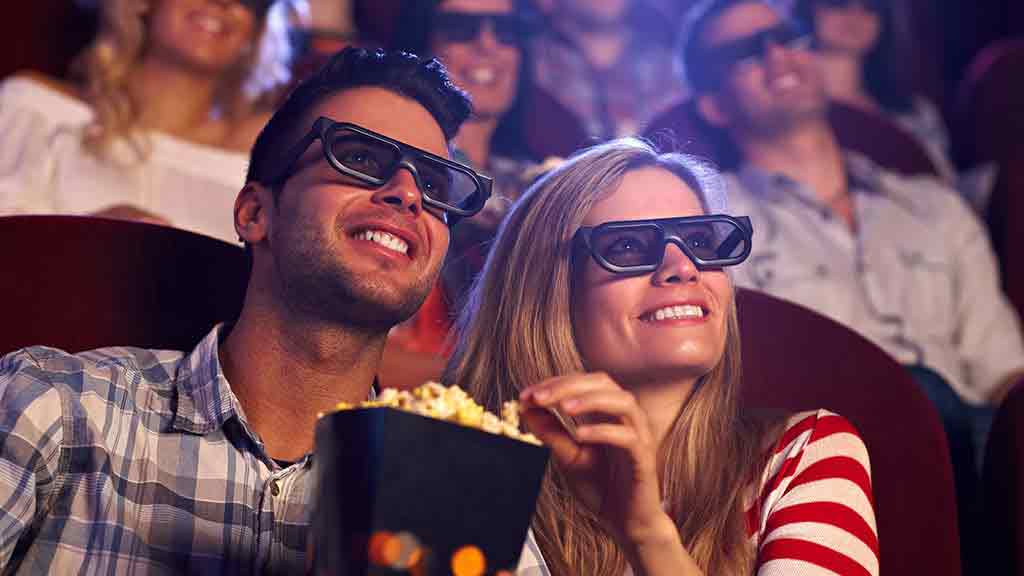 couple watching movie in cinema eating popcorn