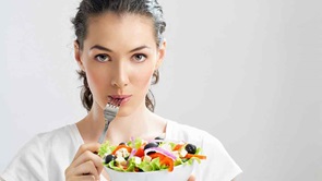 woman with fork in mouth eating salad