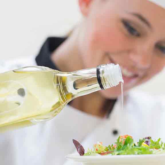 chefs pours oil on salad square