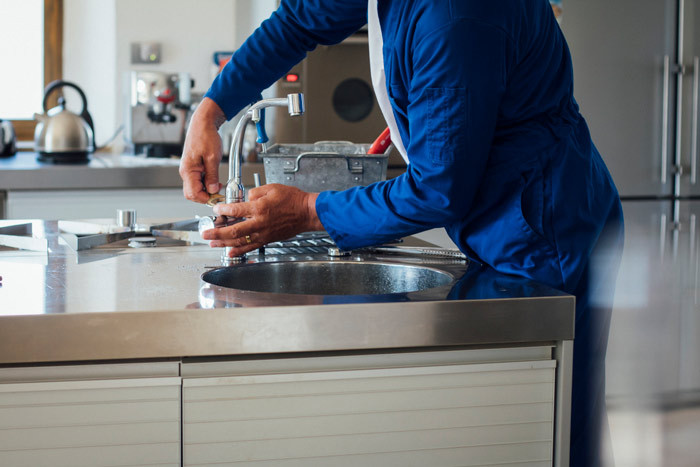 plumber fixing tap at home