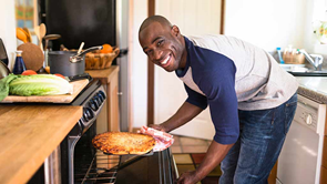 man using oven to cook pizza