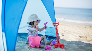 young child at the beach under a beach shelter