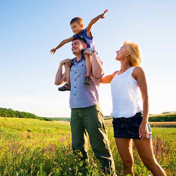 mother and father with child on shoulders outside square