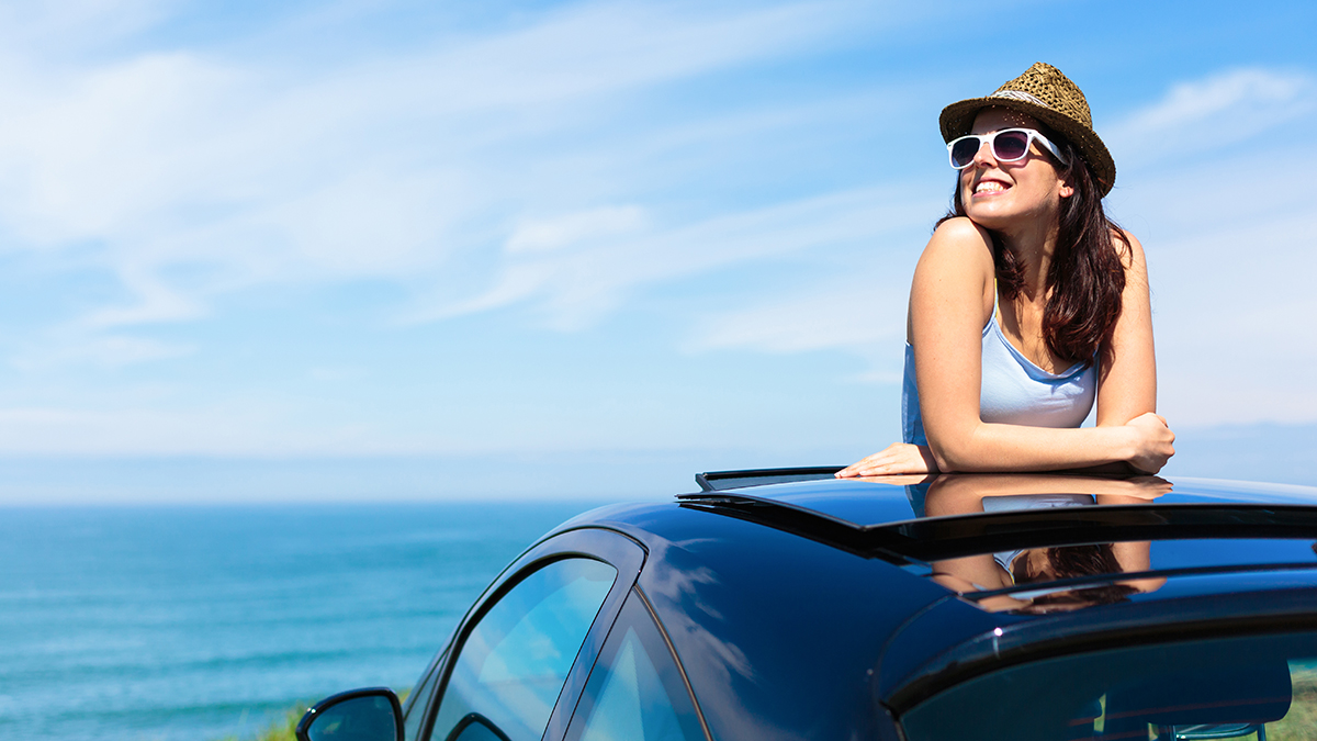 person leaning out of car sunroof enjoying the view on holidays
