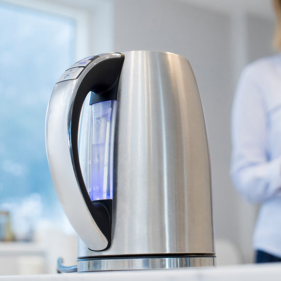 woman using kettle in kitchen sq