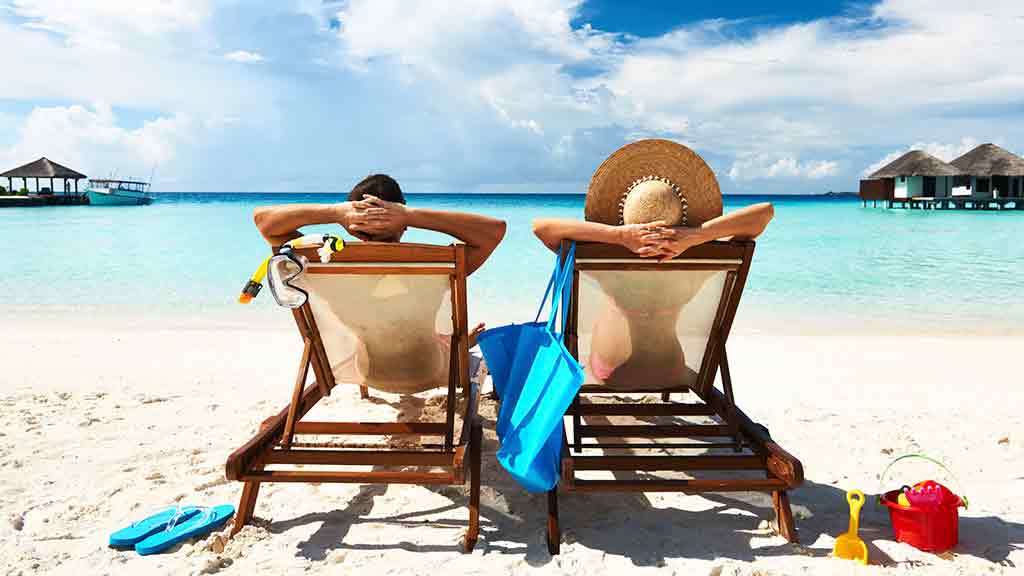 couple relaxing in lounge chairs on a beach