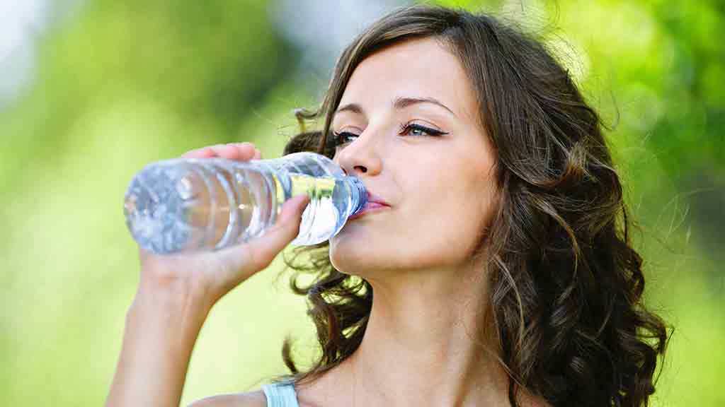 woman drinking water from plastic bottle