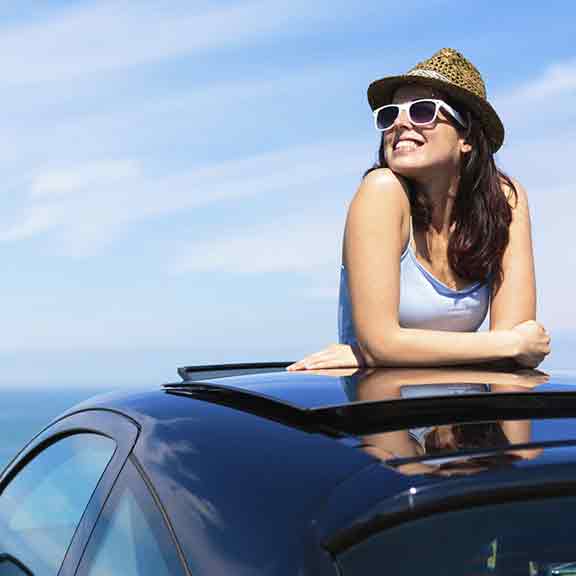 woman pokes head out of car sun roof square