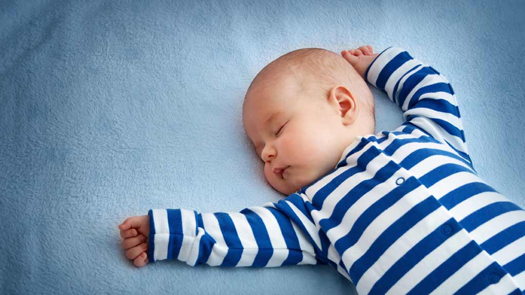 young baby asleep on bed