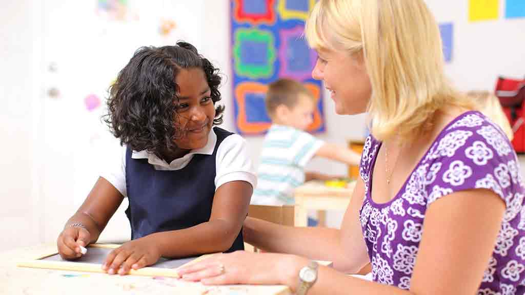 teacher talking with child in classroom