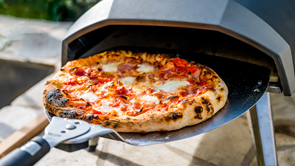 freshly made pizza coming out of a pizza oven