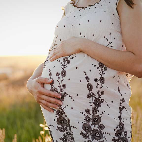 pregnant woman standing in a field square