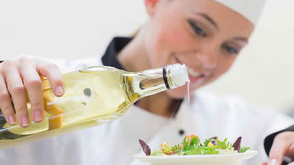 chef pours oil on salad
