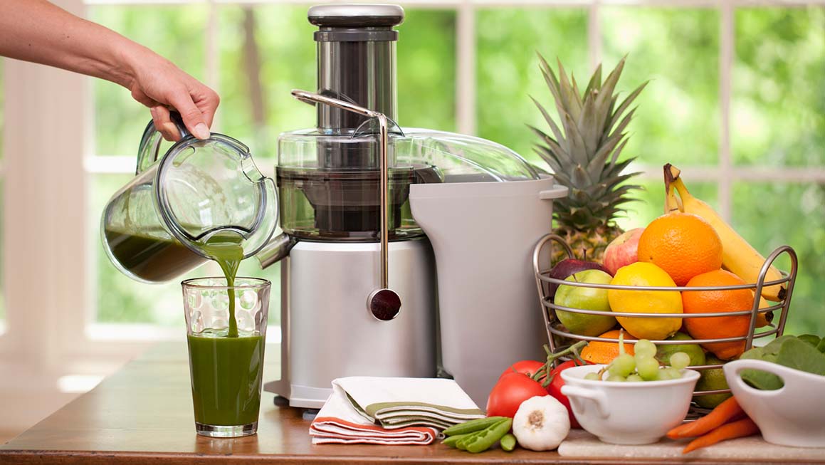 woman using juicer to make green juice