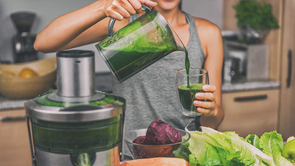 woman using juicer to make green juice