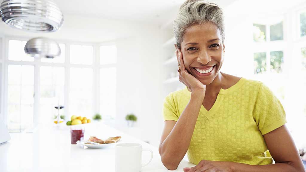 middle aged woman smiles at camera with chin on hand