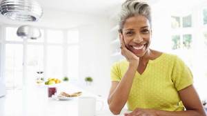 middle aged woman smiles at camera with chin on hand