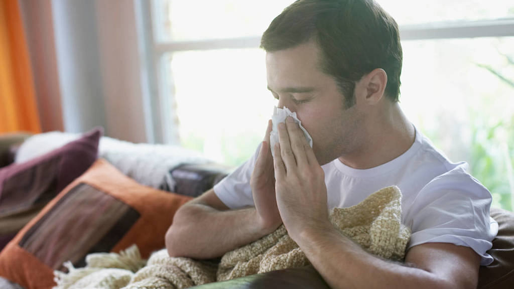 man with a cold blowing his nose