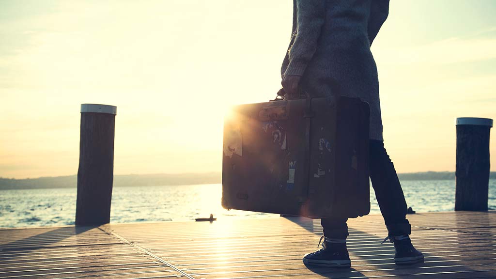 woman waiting on dock with suitcase