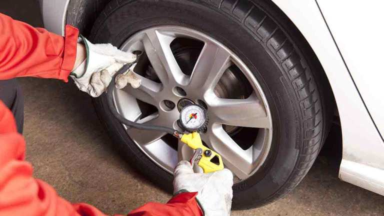 person testing car tyre pressure gauge