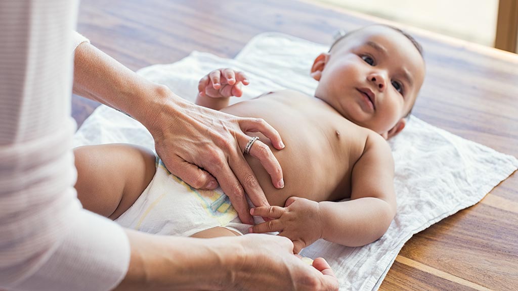 mother putting a nappy on a baby huggies