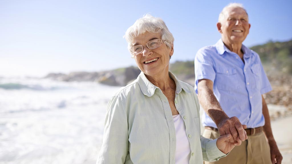 elderly couple walking on the beach