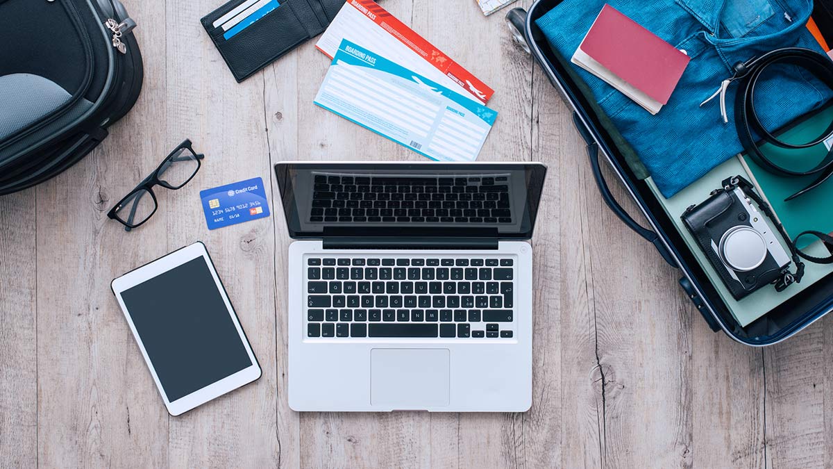 flatlay of devices to take travelling iphone tablet headphones adaptors
