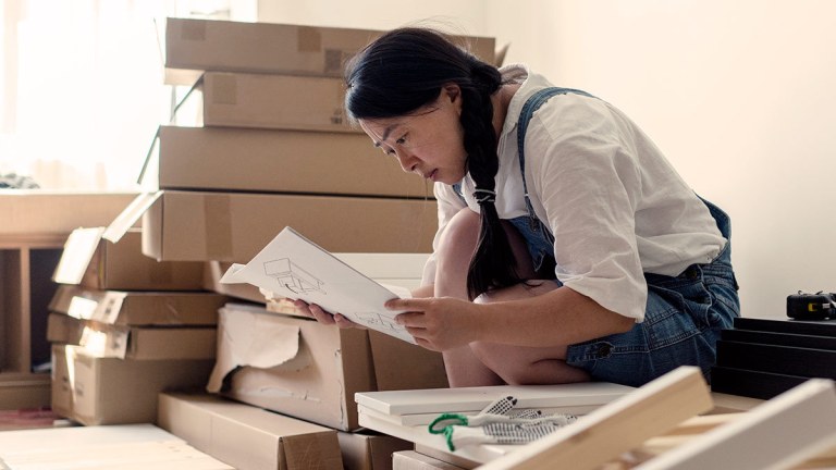 person looking at instructions to assemble set of drawers for nursery