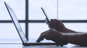 person entering two factor authentication from their smartphone on a laptop