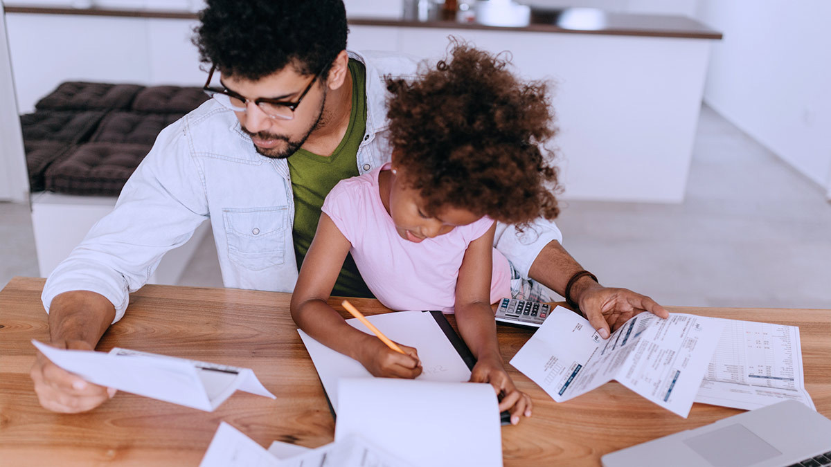 young_parent_going_through_finances_at_home_while_looking_after_daughter