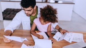 young_parent_going_through_finances_at_home_while_looking_after_daughter