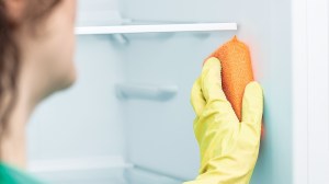 Person cleaning the fridge with a sponge