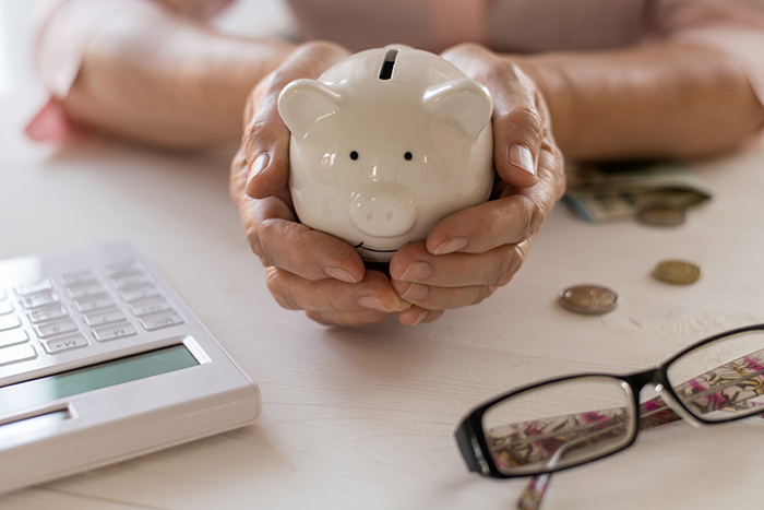 senior_persons_hands_holding_a_piggy_bank