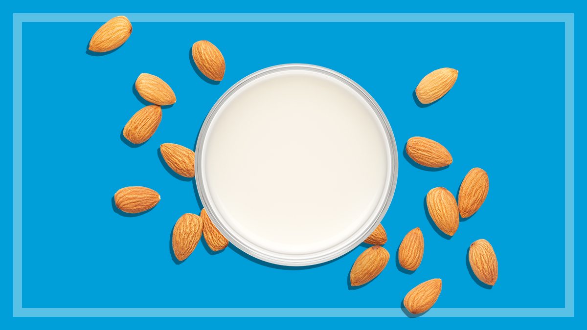above view of almond milk in a glass surrounded by almonds