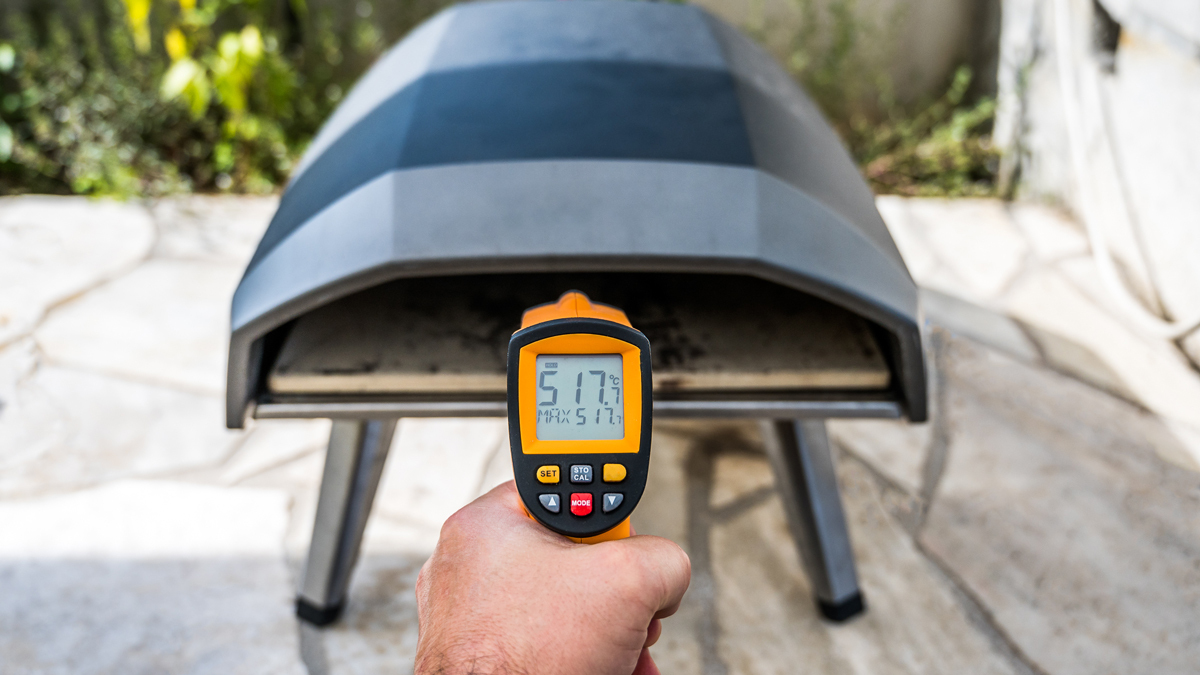 person checking the temperature of an outdoor pizza oven