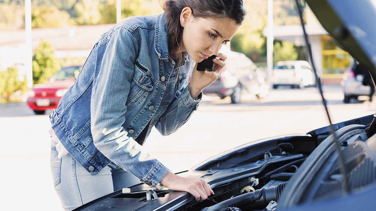 person checking under bonnet of broken down car