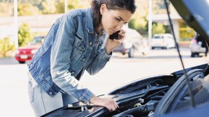 person checking under bonnet of broken down car
