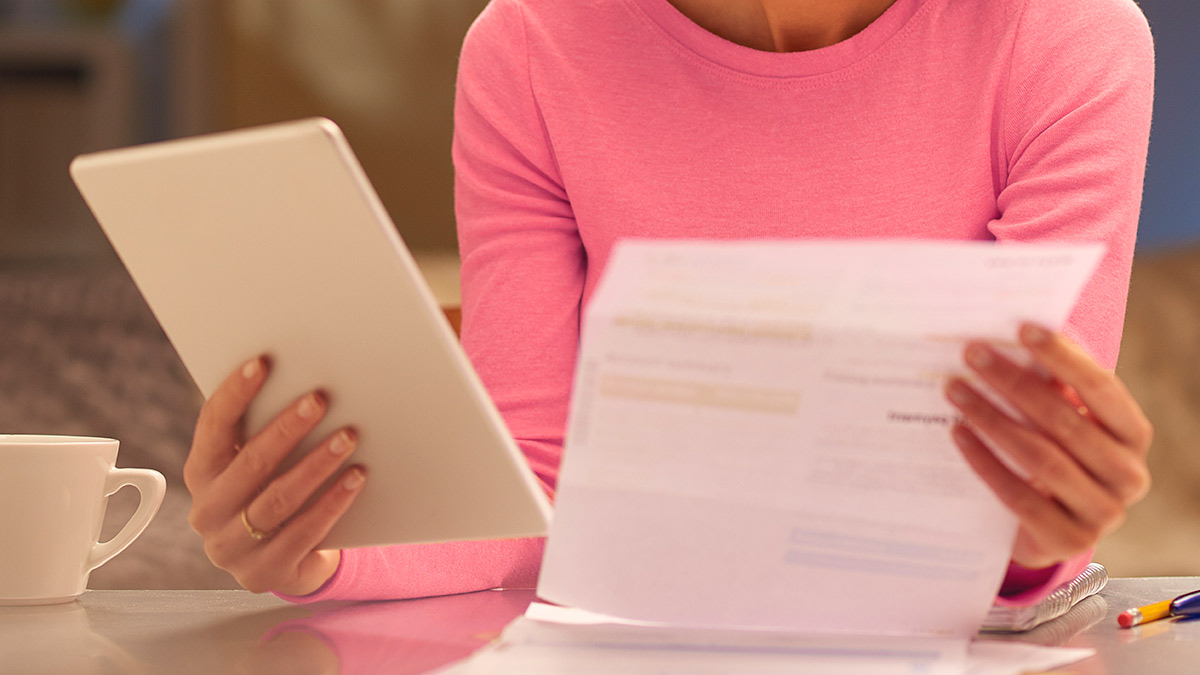 person holding current electricity bill and checking on website