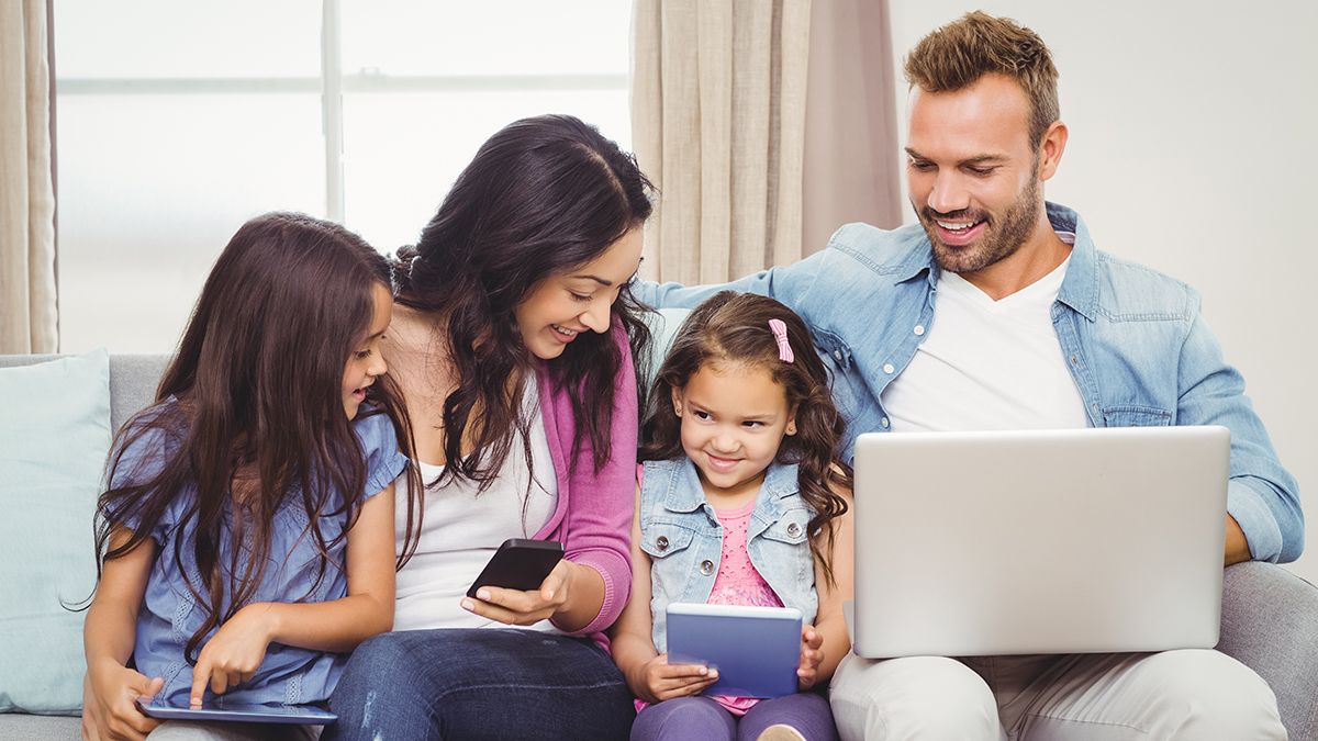 family sitting using multiple smart devices in the home