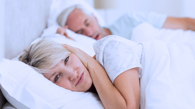 woman covering ears man snoring lead