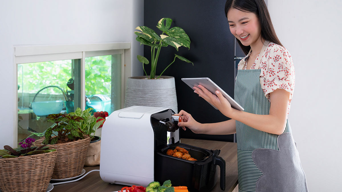 person using an air fryer to cook chicken
