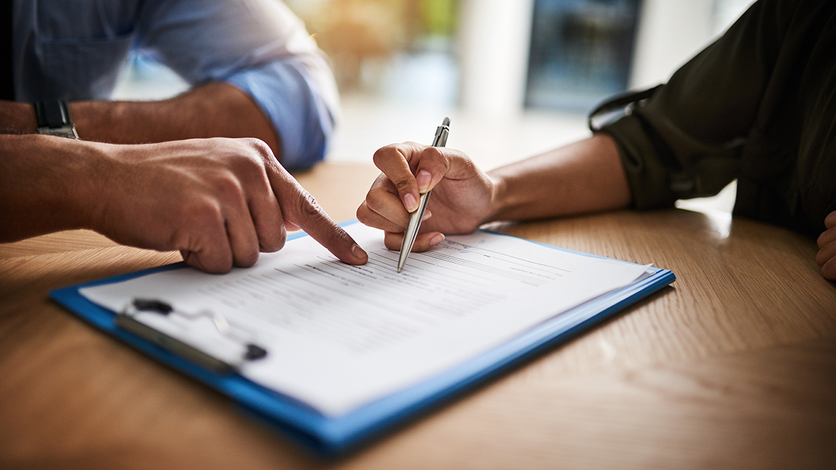 salesperson pointing at place on form where person needs to sign