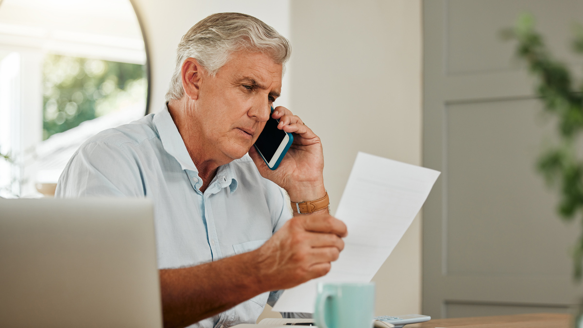 man_talking_on_phone_looking_over_paperwork