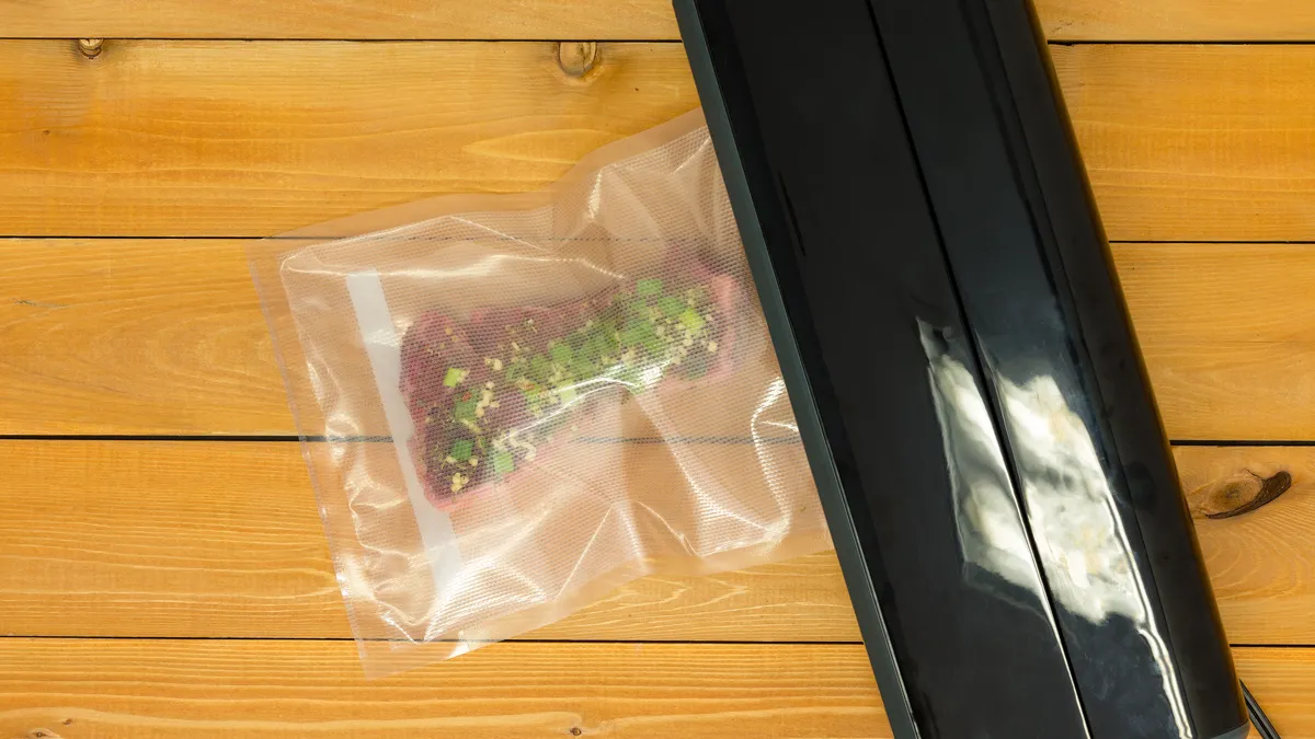 vacuum sealer sealing meat on a wooden board