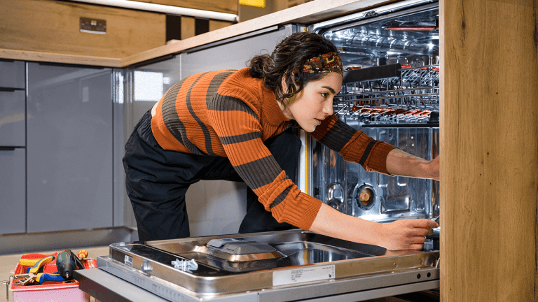 woman reaching into a dishwasher