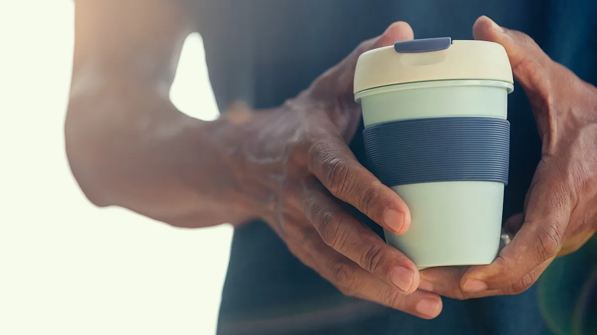 closeup of person holding a reusable coffee cup