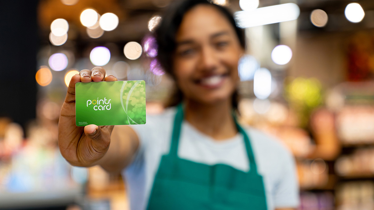 supermarket worker holding loyalty card in store