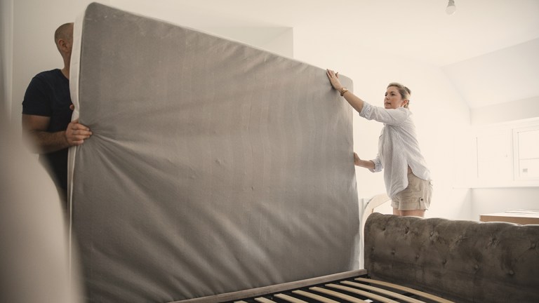 couple removing old mattress from bed