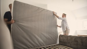 couple removing old mattress from bed